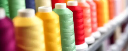 Close-up image of colorful spools of embroidery threads arranged in a row, highlighting the wide variety of thread shades available at Dhaga-Raga for personalized embroidery creations