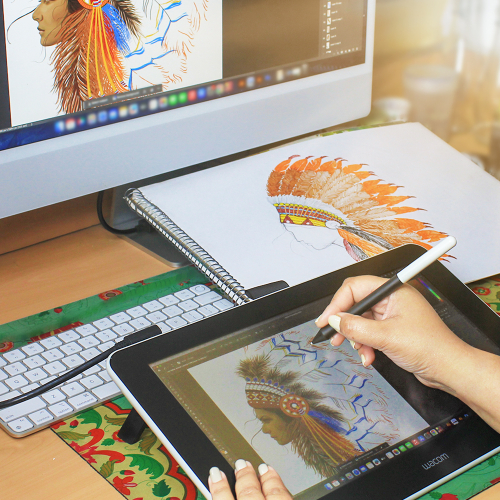  A designer working on a digital tablet to create a personalized embroidery artwork, with a hand-drawn sketch and the same design on a computer screen, illustrating the custom design process at Dhaga-Raga