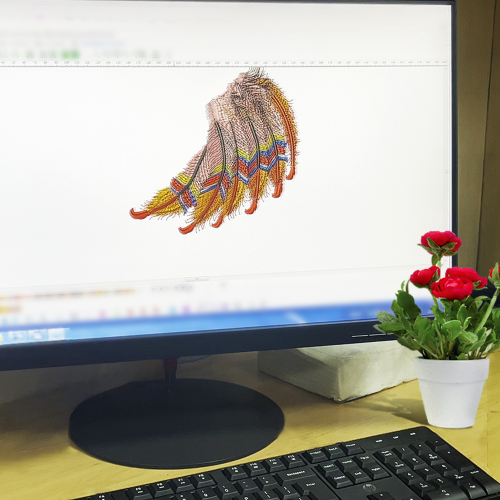 A computer screen displaying the digitization of an intricate embroidery design featuring colorful feathers, representing the digital embroidery file preparation stage in Dhaga-Raga’s personalization process