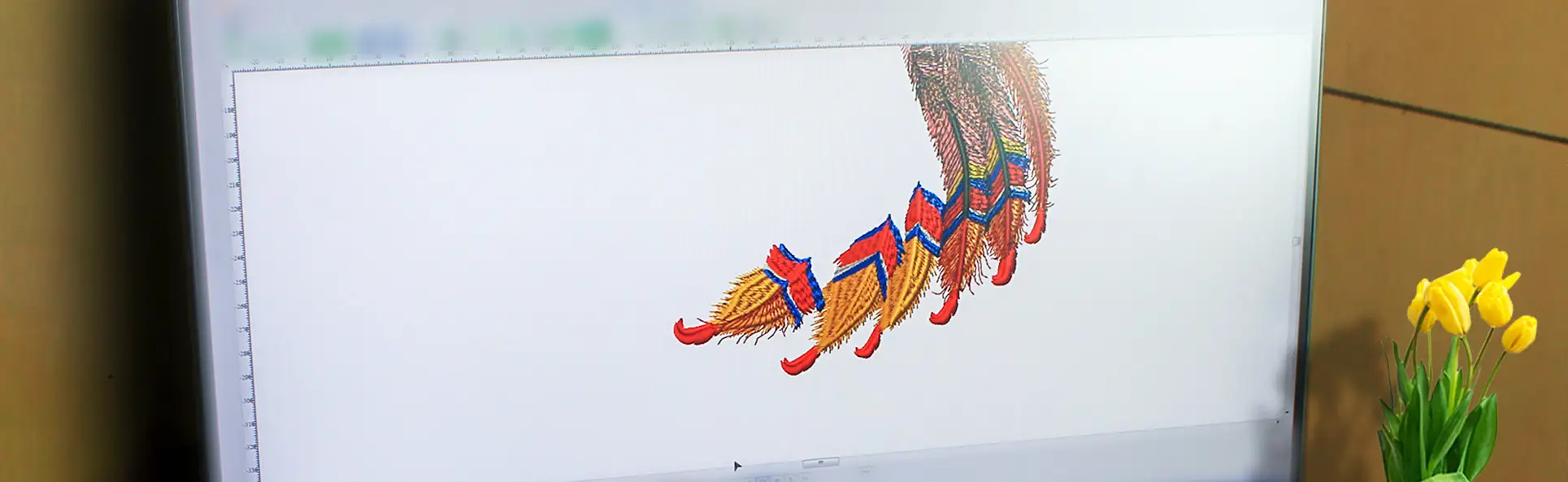 Computer screen displaying the digitized embroidery design of colorful feathers, highlighting the digitizing stage of the embroidery process
