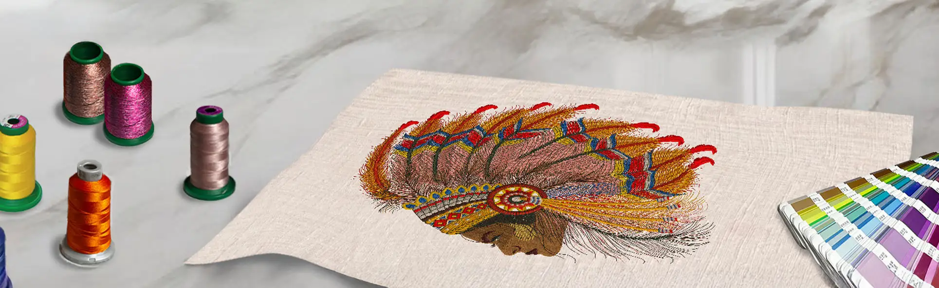 Completed colorful embroidery design on fabric, surrounded by vibrant thread spools on a marble surface