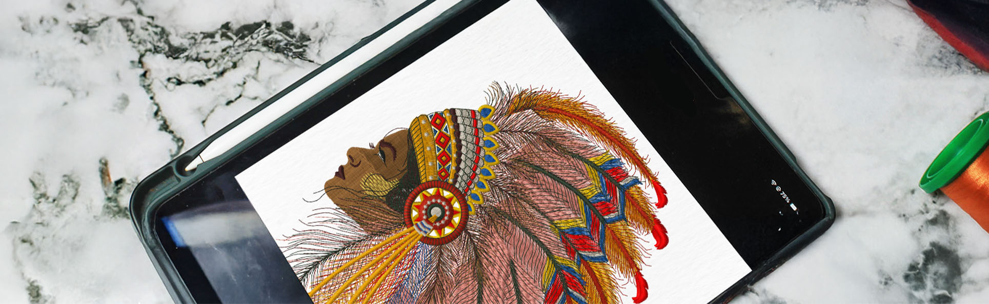 Tablet displaying a detailed embroidered design artwork on a marble table, showcasing the final visualization of the embroidery process