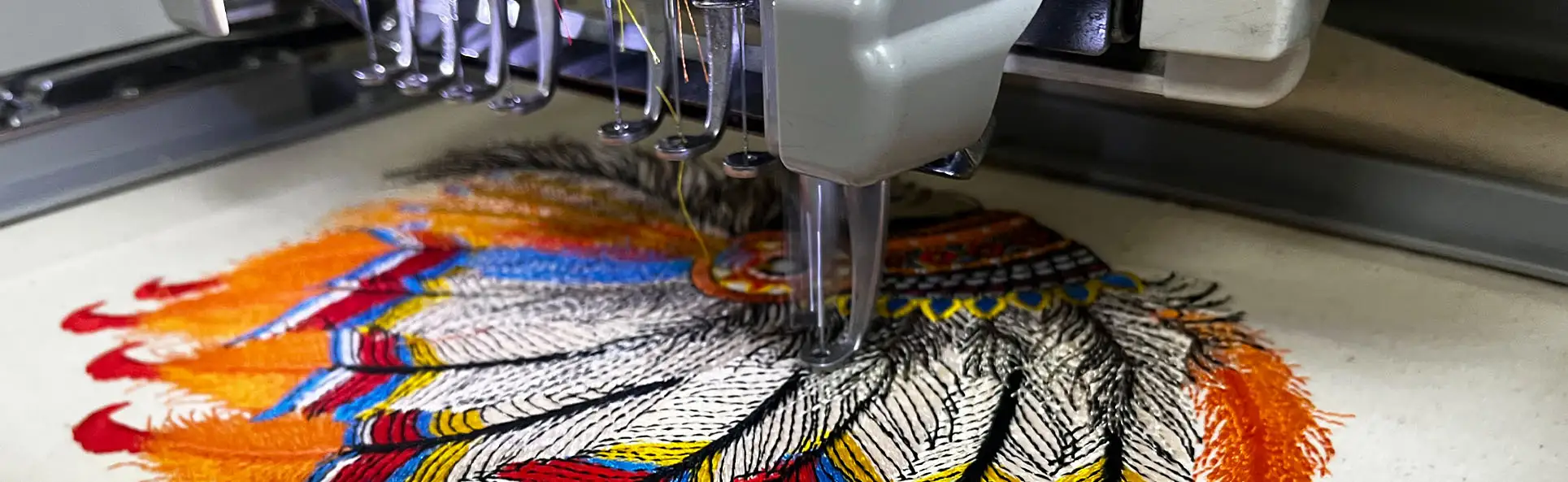 Embroidery machine detailing colorful feather design on fabric with precision stitching