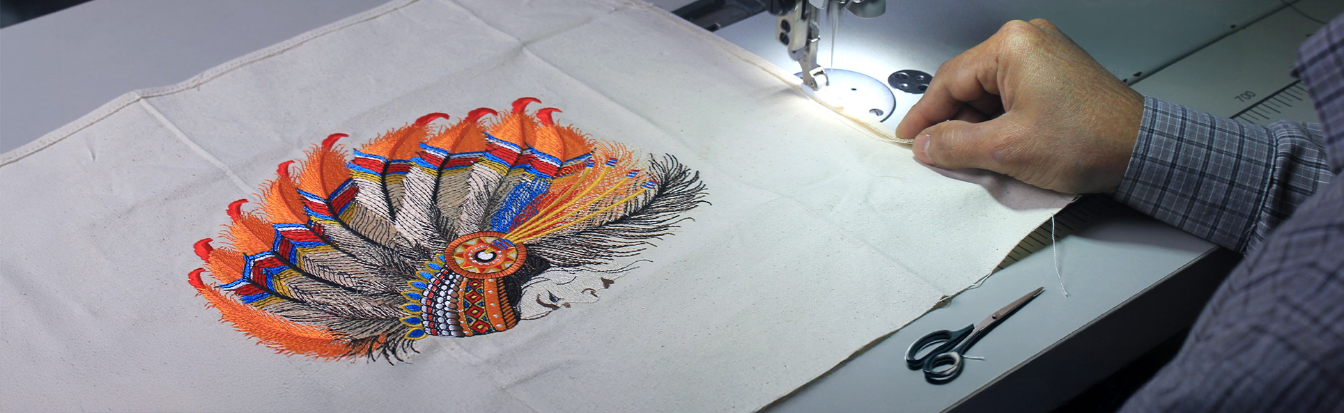 Tailoring process with detailed embroidery artwork being stitched onto fabric using a sewing machine
